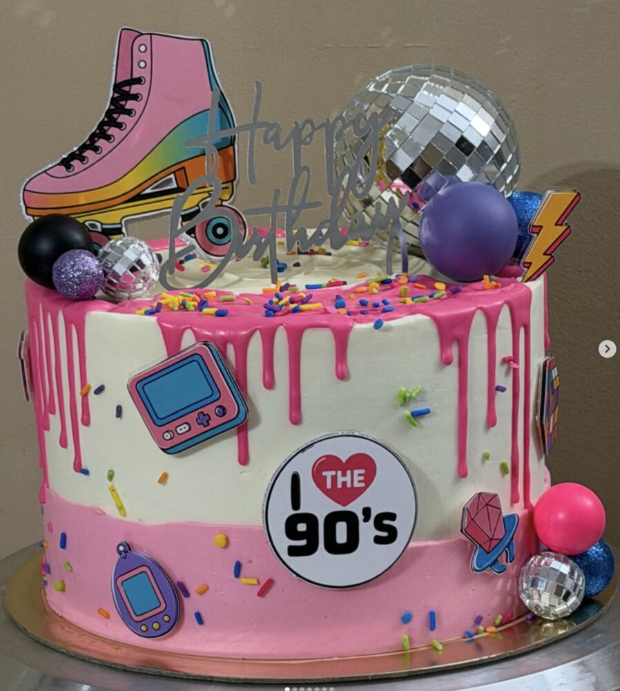 Pink 90s-themed birthday cake with roller skate cake topper and disco balls
