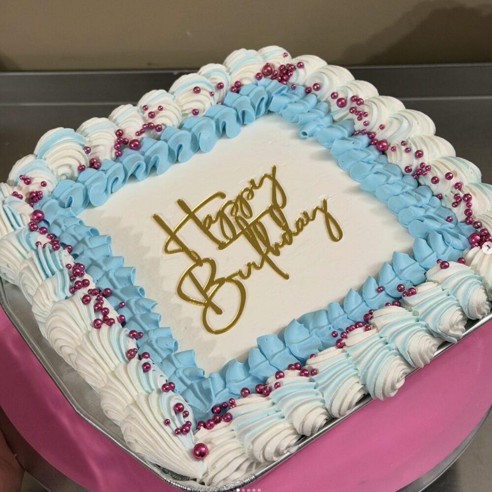 Square birthday cake with blue and white shell piping and pink pearl accents