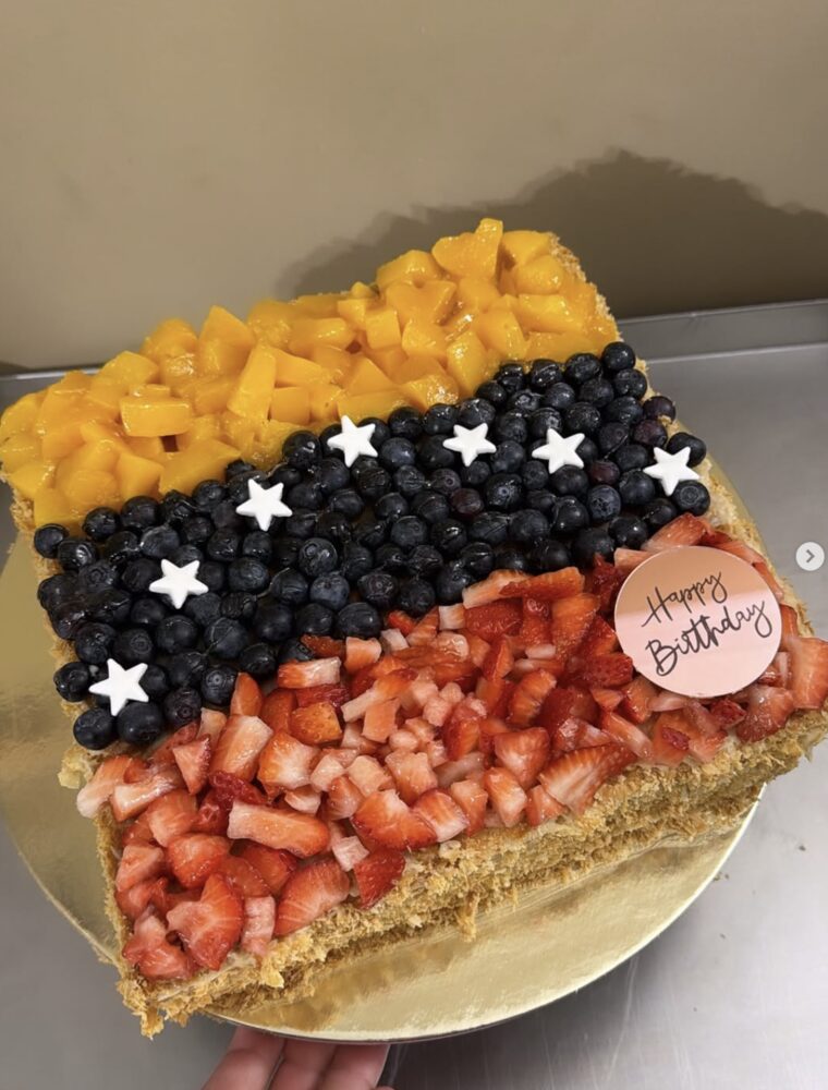 Tres leches cake topped with sliced mango, blueberries and strawberries