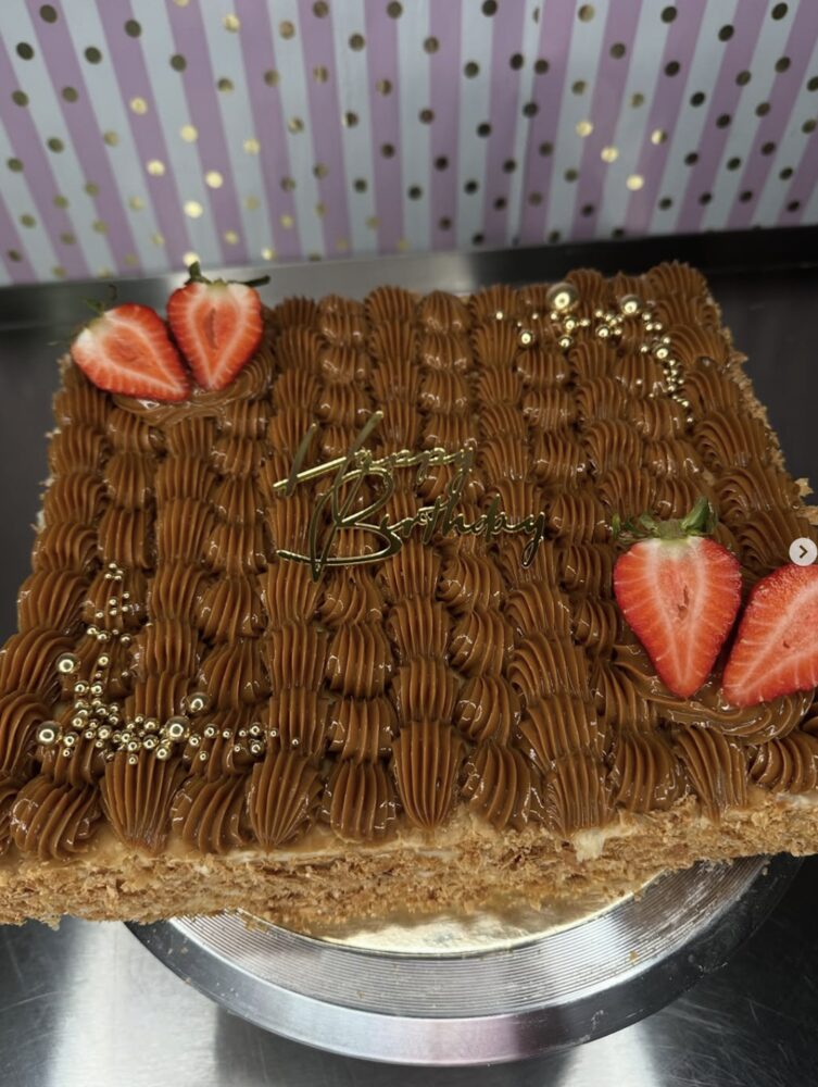 Square dulce de leche cake piped with caramel buttercream and topped with fresh strawberries